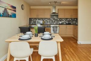 een keuken met een houten tafel en witte stoelen bij Stylish 2-Bedroom Apartment with Free Parking in Halifax