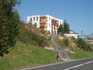 una persona montando una bicicleta por una carretera junto a un edificio en Penzion Partizan, en Vysoke Tatry - Horny Smokovec