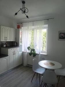 een keuken met witte kasten en een tafel en een raam bij relax apartament in Skarżysko-Kamienna