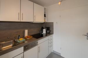 una cucina con armadi bianchi e lavandino di Ferienwohnung Uasterfuar a Hörnum