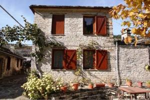 un edificio con finestre rosse e un tavolo di fronte ad esso di Papigo Astraka II a Papigko