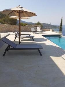 duas mesas de piquenique com um guarda-sol ao lado de uma piscina em Ionian Stone Luxury Villas em Nikiana