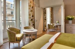 Habitación de hotel con cama, mesa y sillas en Hôtel Château Frontenac, en París