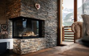 einen Steinkamin im Wohnzimmer mit Fenster in der Unterkunft Bergwelt Grindelwald Residence in Grindelwald