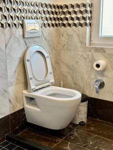 aseo blanco con asiento en el baño en Zeus Hotel, en Shëngjin