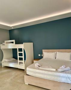 1 dormitorio con litera blanca y pared azul en Zeus Hotel, en Shëngjin