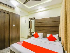 Schlafzimmer mit einem Bett mit orangefarbenen und roten Kissen in der Unterkunft StayGuru Hotel Atithi in Bhuj