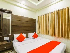 Schlafzimmer mit einem Bett mit orangefarbenen und weißen Kissen in der Unterkunft StayGuru Hotel Atithi in Bhuj