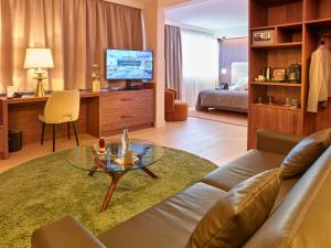 een woonkamer met een bank, een tafel en een televisie bij Best Western Plus Metz Technopole in Metz