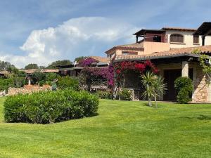 ein großes Haus mit einem Hof mit grünem Gras in der Unterkunft Porto Coda Cavallo Salina Bamba in Capo Coda Cavallo