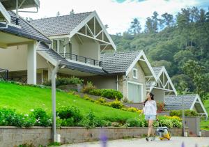 een vrouw die voor een huis loopt met haar bagage bij AJ Gable Clouds Ooty by VOYE HOMES - Serene Stay Near Avalanche Emerald Lake in Ooty