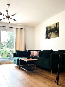 ein Wohnzimmer mit einem grünen Sofa und einem Tisch in der Unterkunft 2 ZKB Apartment in Mannheim Küche - Parken - Großer TV in Mannheim