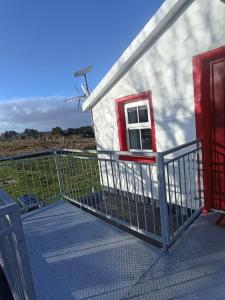 une maison avec une clôture et une éolienne dans l'établissement Tiernan's Luxury Cottages, à Charlestown