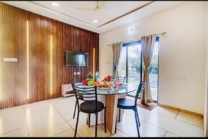 une salle à manger avec une table, des chaises et une télévision dans l'établissement OCEAN CREST LUXURY VILLA Mahabaleshwar, à Mahabaleshwar