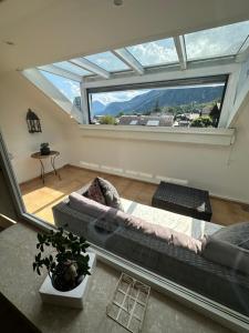 a living room with a couch and a large window at Nannerls Penthouse in Sankt Gilgen