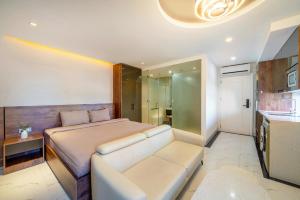 NM Apartment Beach Da Nang في دا نانغ: غرفة نوم بسرير واريكة ومطبخ