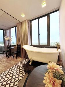 - une salle de bains avec baignoire dans une chambre dotée de fenêtres dans l'établissement TTR Skypool View Hotel, à Đà Lạt