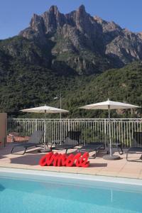 une piscine avec des chaises et des parasols et une montagne dans l'établissement Capo D'orto - Porto - Corse, à Porto Ota