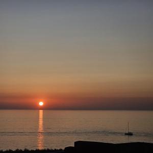 een zonsondergang over de oceaan met een boot in het water bij Casa Vacanza Portu Maga (Marina di Arbus-Sardegna) in Portu Maga