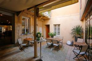 een patio met tafels en stoelen en een gebouw bij The Originals Boutique, Hôtel de la Paix, Beaune in Beaune