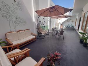 - un salon avec un canapé et une table avec un parasol dans l'établissement Ravenala Paracas Hostel, à Paracas