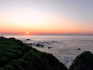 una puesta de sol sobre el océano con rocas en el agua en HOTEL HOLISTIC RESORT - Vacation STAY 34557v, en Taiji