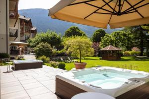 een hot tub op een patio met een parasol bij Hotel Lido - green & slow life in Molveno