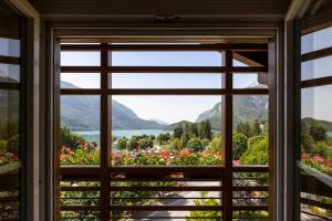 een raam met uitzicht op de bergen vanuit een huis bij Hotel Lido - green & slow life in Molveno