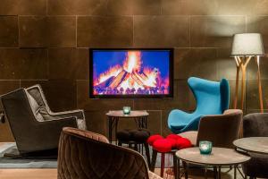 een lobby met stoelen en een tv aan de muur bij Motel One Freiburg in Freiburg im Breisgau