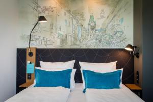 een slaapkamer met een bed met twee blauwe kussens bij Motel One Freiburg in Freiburg im Breisgau