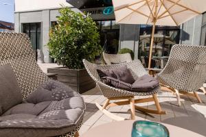 een patio met 3 stoelen en een tafel met een parasol bij Motel One Freiburg in Freiburg im Breisgau