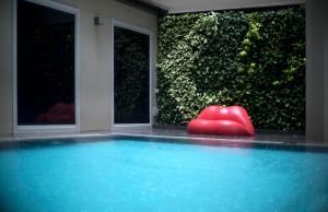 a pool with a red object in front of a hedge at V Hotel Bencoolen in Singapore