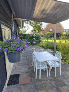 d'une terrasse avec une table blanche, des chaises et des fleurs. dans l'établissement Logeren bij De Soerensesteeg, à Uddel