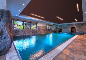 ein Pool in einem Haus mit einer Felswand in der Unterkunft Hotel Selva in Folgarida