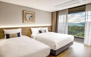 two beds in a hotel room with a window at Kensington Resort Gyeongju in Gyeongju