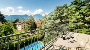 un balcone con tavolo, sedie e piscina di Hotel Villa Laurus a Merano