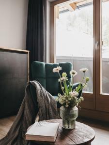 Zimmer mit einem Tisch mit einer Vase aus Blumen und einem Stuhl in der Unterkunft VAYA Zell am See in Zell am See