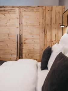 ein Bett mit weißen Kissen und einer Holzwand in der Unterkunft VAYA Zell am See in Zell am See