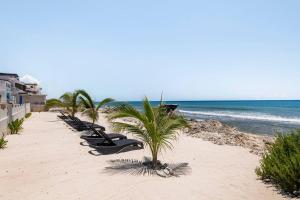 uma fila de espreguiçadeiras pretas numa praia em Villas Najo' Isla Mujeres. em Ilha das Mulheres