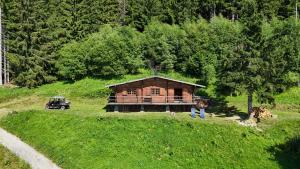 uma casa no topo de uma colina gramada ao lado de uma floresta em Chalet d'alpage avec vue incroyable em Saint-Gervais-les-Bains