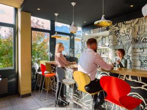 un groupe de personnes assises au bar d'un restaurant dans l'établissement ibis Luzern Kriens, à Lucerne