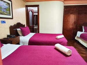 um quarto de hotel com duas camas com lençóis cor-de-rosa em Hotel Diamante Azul em La Paz