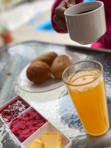 une table avec une assiette de nourriture et un verre de jus d'orange dans l'établissement Ravenala Paracas Hostel, à Paracas