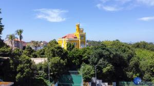 un bâtiment jaune avec une tour au sommet des arbres dans l'établissement Vila Aurora, à Luso