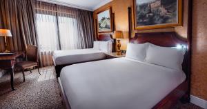 a hotel room with two beds and a desk at Palazzo Hotel in Johannesburg