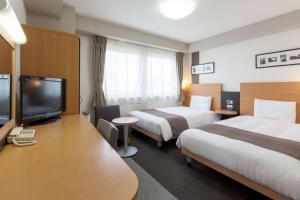 a hotel room with two beds and a flat screen tv at Comfort Hotel Himeji in Himeji