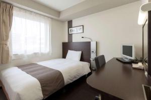 a hotel room with a bed and a desk with a computer at Comfort Hotel Himeji in Himeji