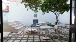 een patio met een tafel en stoelen en een boom bij Gala Placida 1923 in Granada