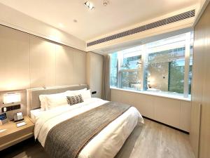 - une chambre avec un grand lit et une fenêtre dans l'établissement CM Serviced Apartment Shenzhen Dongmen, à Shenzhen