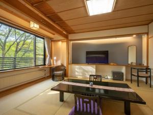 ein Wohnzimmer mit einem Tisch und einem großen Fenster in der Unterkunft 蔵王温泉 岩清水料理の宿 季の里 in Zao Onsen